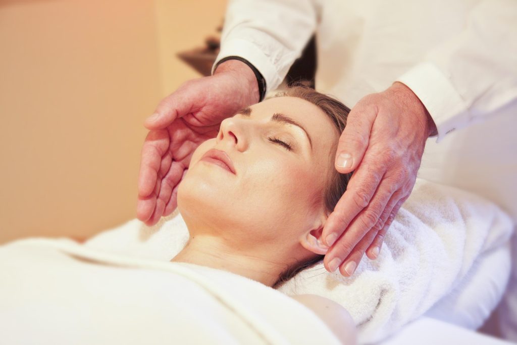 Un praticien reiki qui entoure la tête d’une personne de ses mains